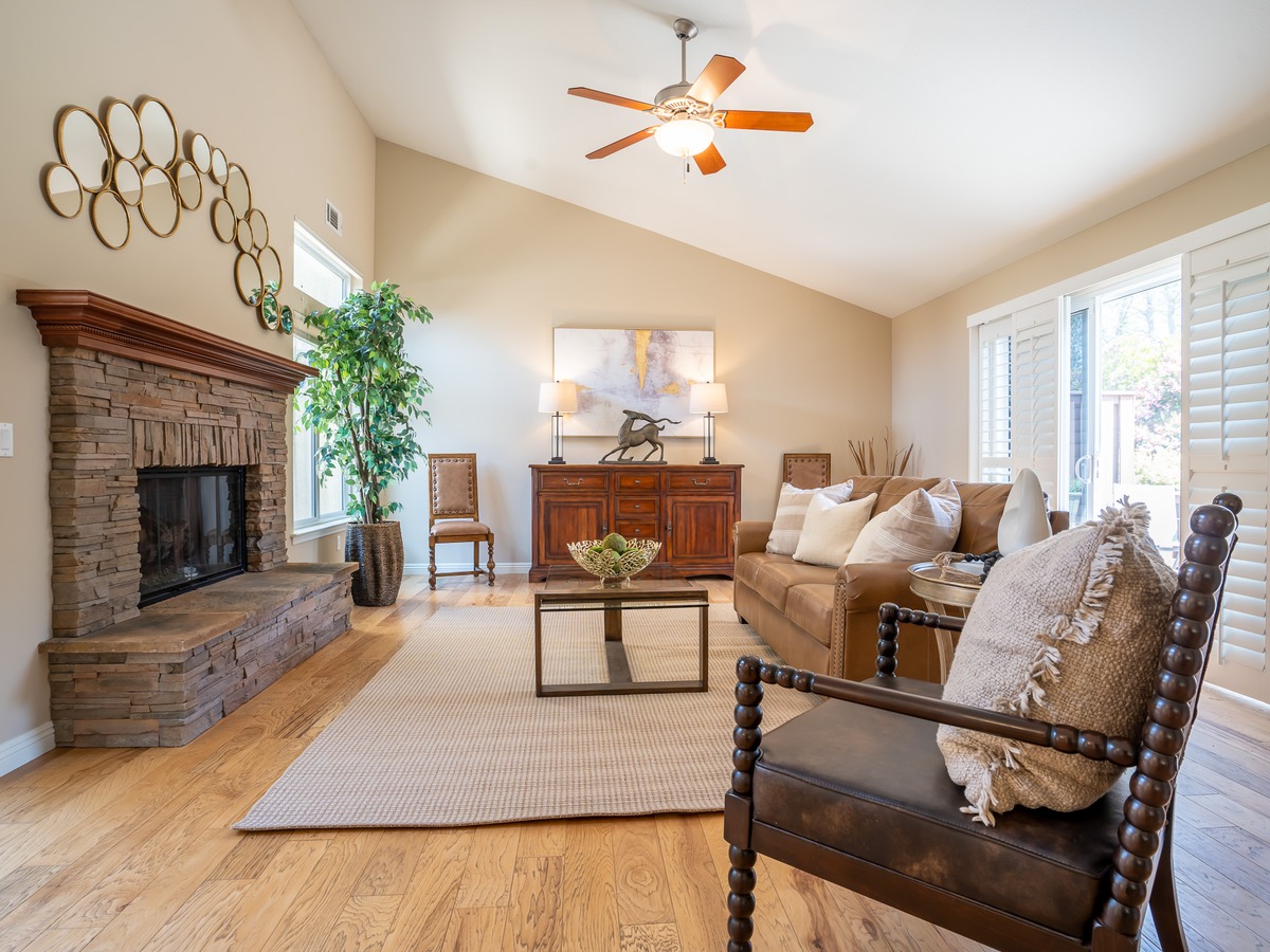 Staged living room with a stone fireplace and vaulted ceiling at a Foxenwood Circle listing